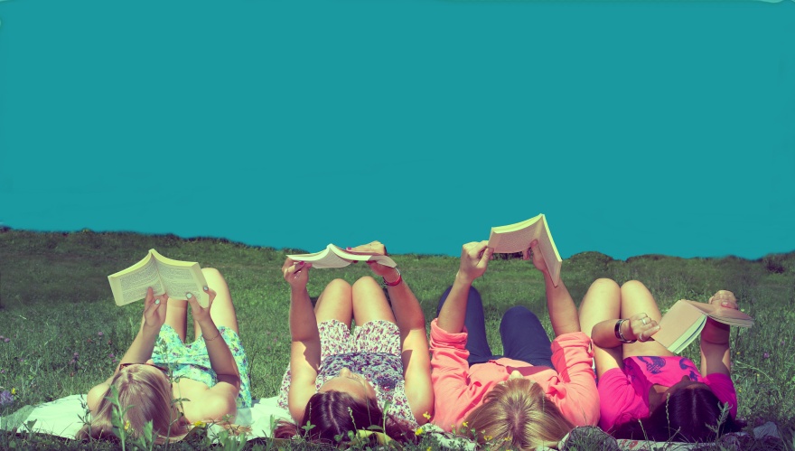 friends reading under sunshine lying on the meadow