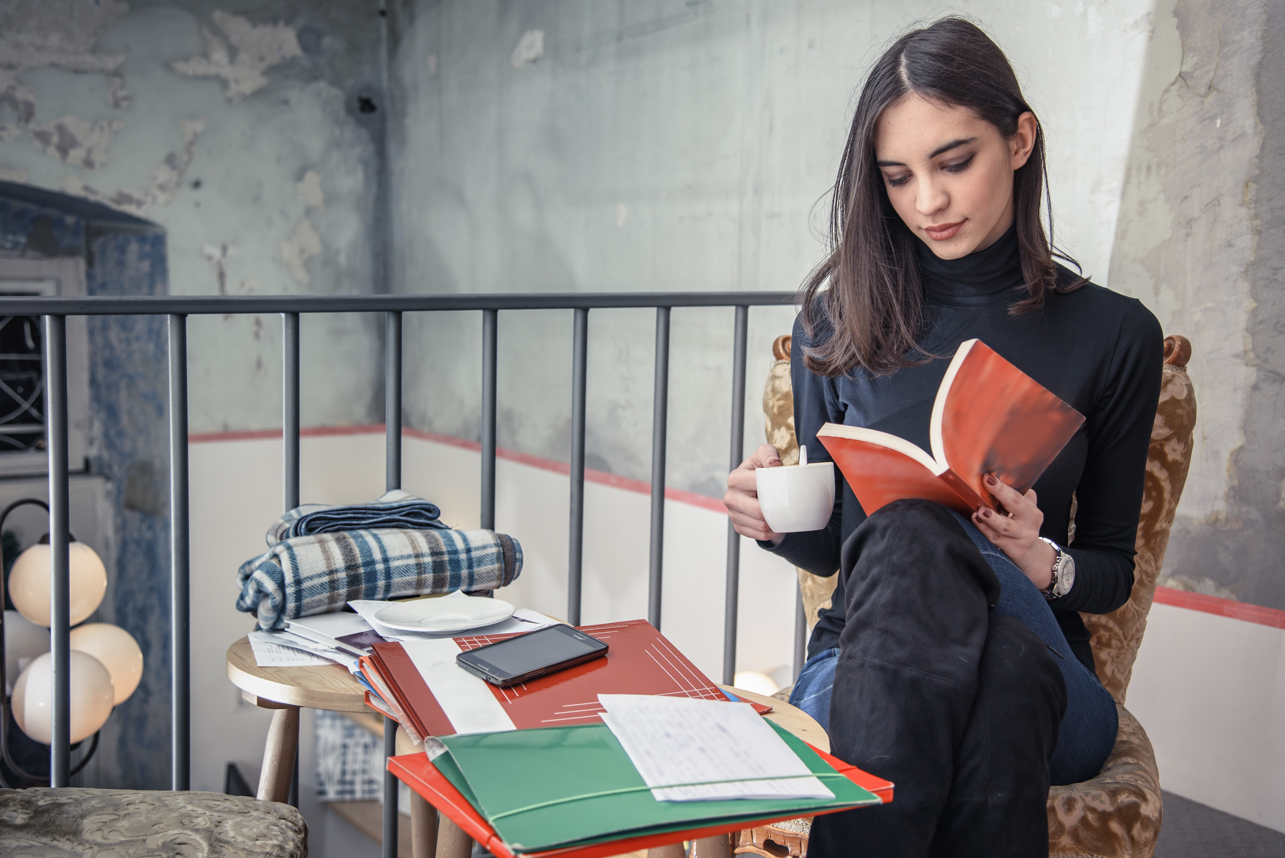 Beautiful girl, a student, reading a book in a coffee shop, enjoying her time alone