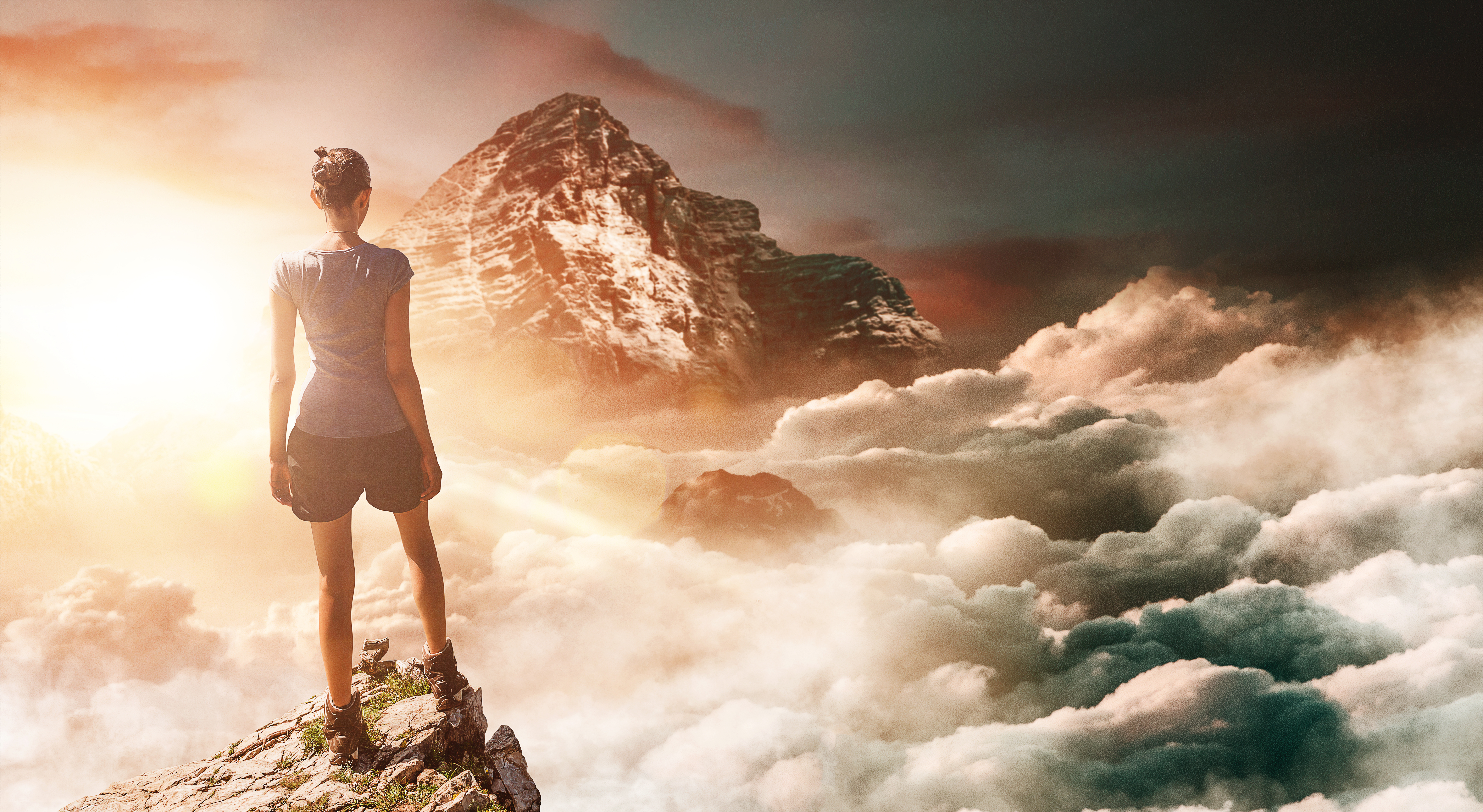 Hiker on peak with tall mountain in background