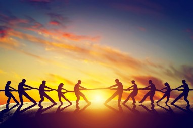 Two groups of people pulling line, playing tug of war. Teamwork